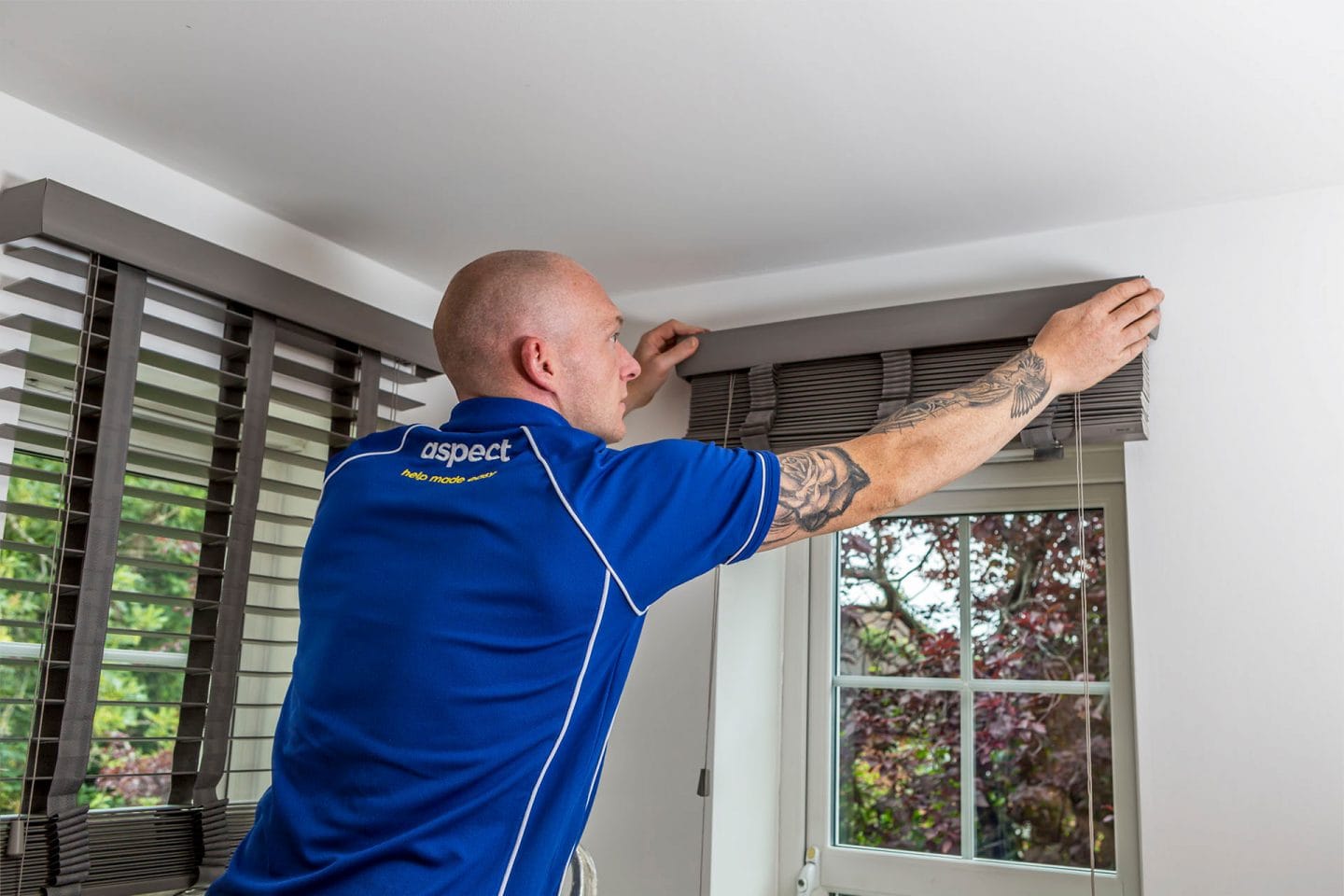 An Aspect handyman fitting a venetian blind to fixings above a window.