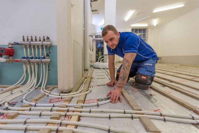 An Aspect heating engineer installing a water-fed underfloor heating system in a commercial property.