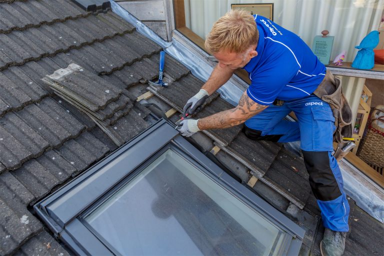 An Aspect roofer removing the flashings around a Velux window on a tiled roof.