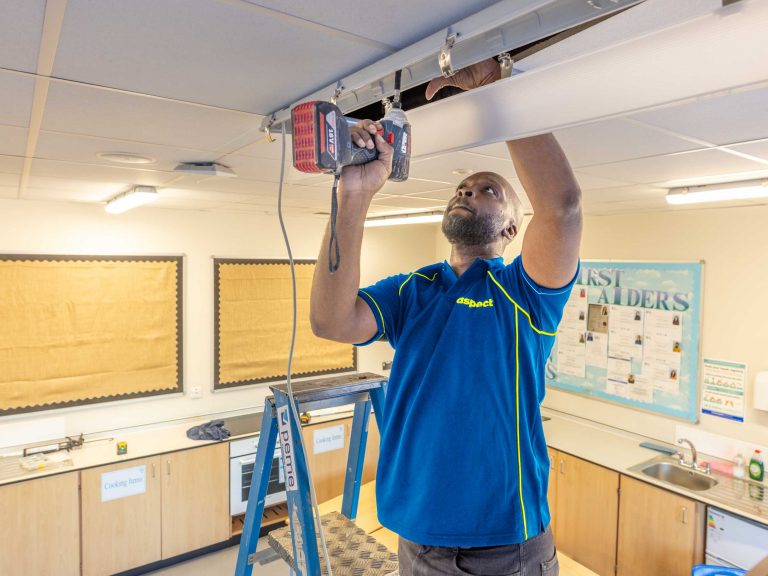 Commercial electrician fitting internal lighting a t a school in London