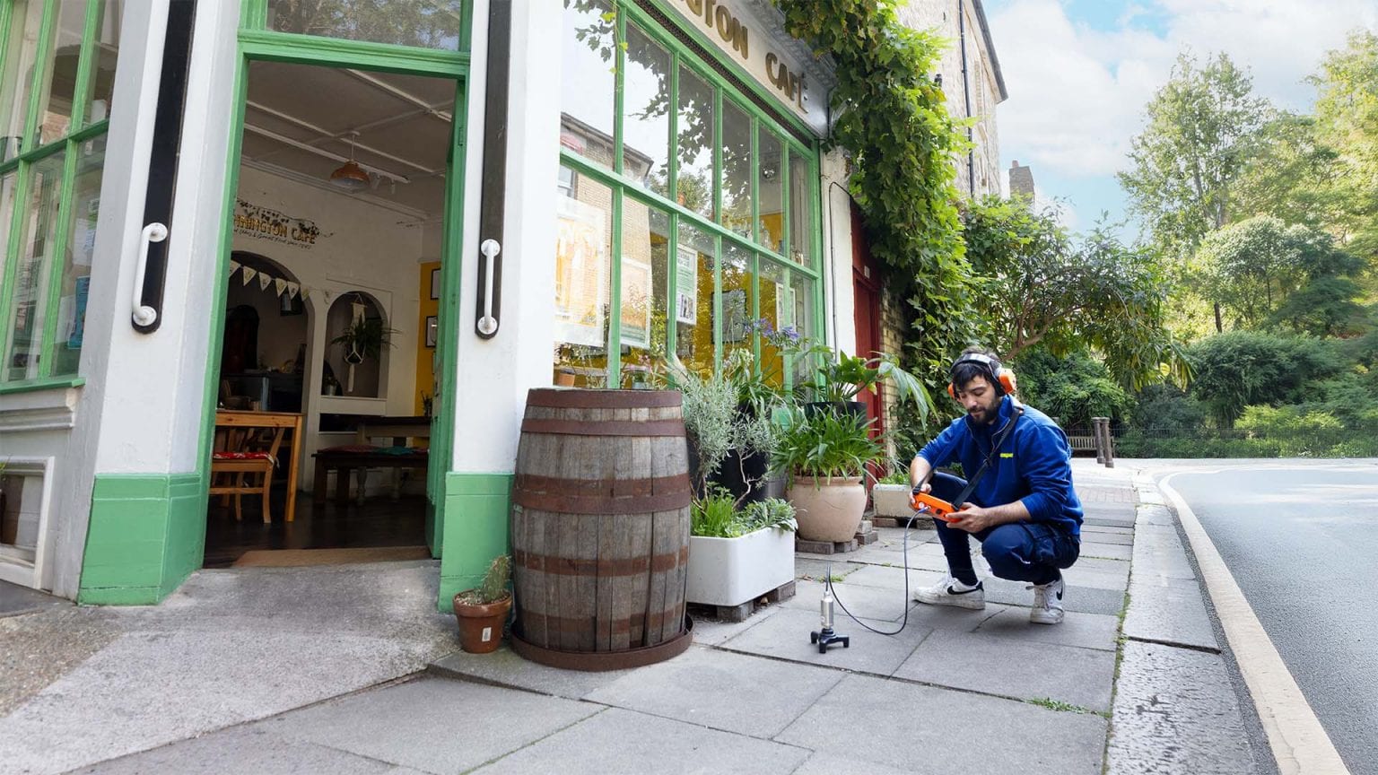 An Aspect leak detection specialist using acoustic equipment outside a cafe and residential property to find a mains water leak.