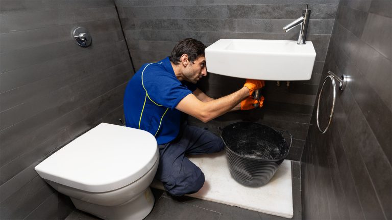 An Aspect plumber fixing a blocked sink in a toilet.