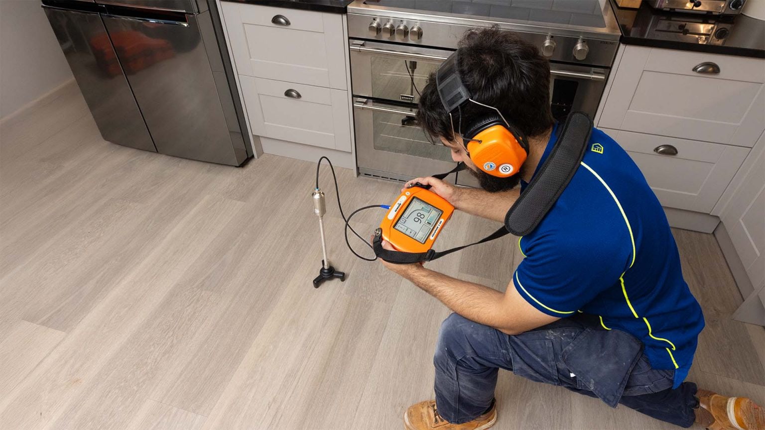 An Aspect tradesperson using an acoustic test to locate a leak in an underfloor central heating system in a domestic kitchen.