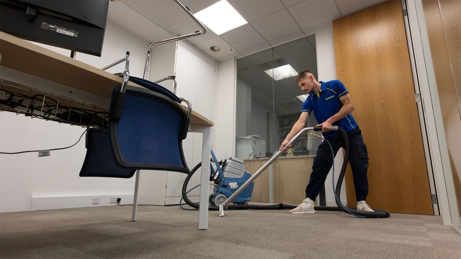 An Aspect cleaning technician cleaning the carpet in a commercial office.