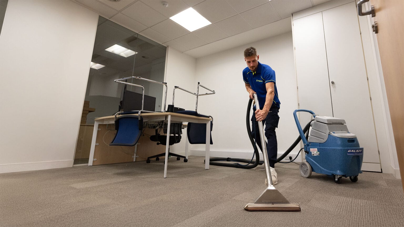 An Aspect tradesperson cleaning the carpet in a commercial propoerty.