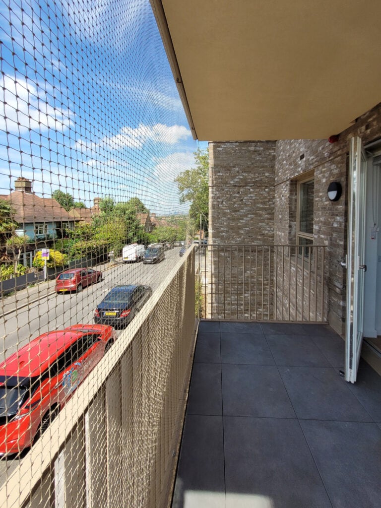 Bird netting installed to deter pigeons from perching on a residential balcony in London