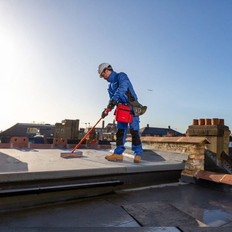 An Aspect roofer using specialist electronic equipment to locate pinhole leaks in a flat roof covered with fibreglass-based product.