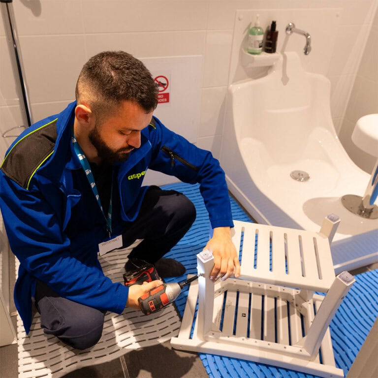 An Aspect tradesperson assembling a small table in a spa treatment room.