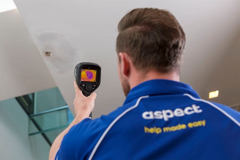 An Aspect leak detection specialist uses a thermal imaging camera on a patch of moisture on a ceiling