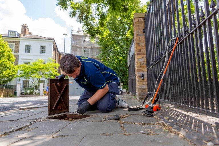 An Aspect leak detection expert takes a reading from a water meter pavement cover.