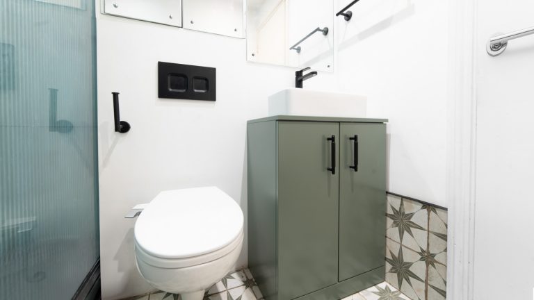 A toilet fitted with a concealed cistern and black flush plate in a residential en-suite bathroom.