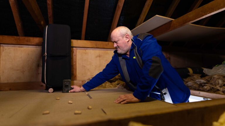 An Aspect pest controller setting motion sensor cameras in an attic for a suspected rodent problem