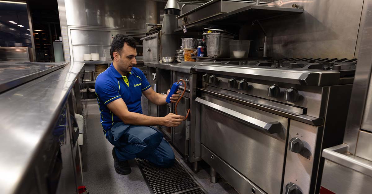 A commercial gas engineer carrying out a gas safety check in a commercial kitchen.