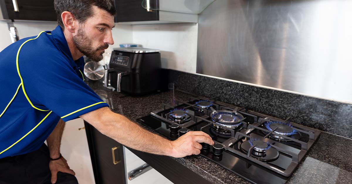 A Gas Safe-registered engineer testing the burners on a gave hob he has just installed.