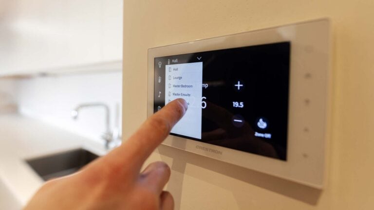 A heating engineer testing the touch screen thermostatic control panel of an underfloor heating system.