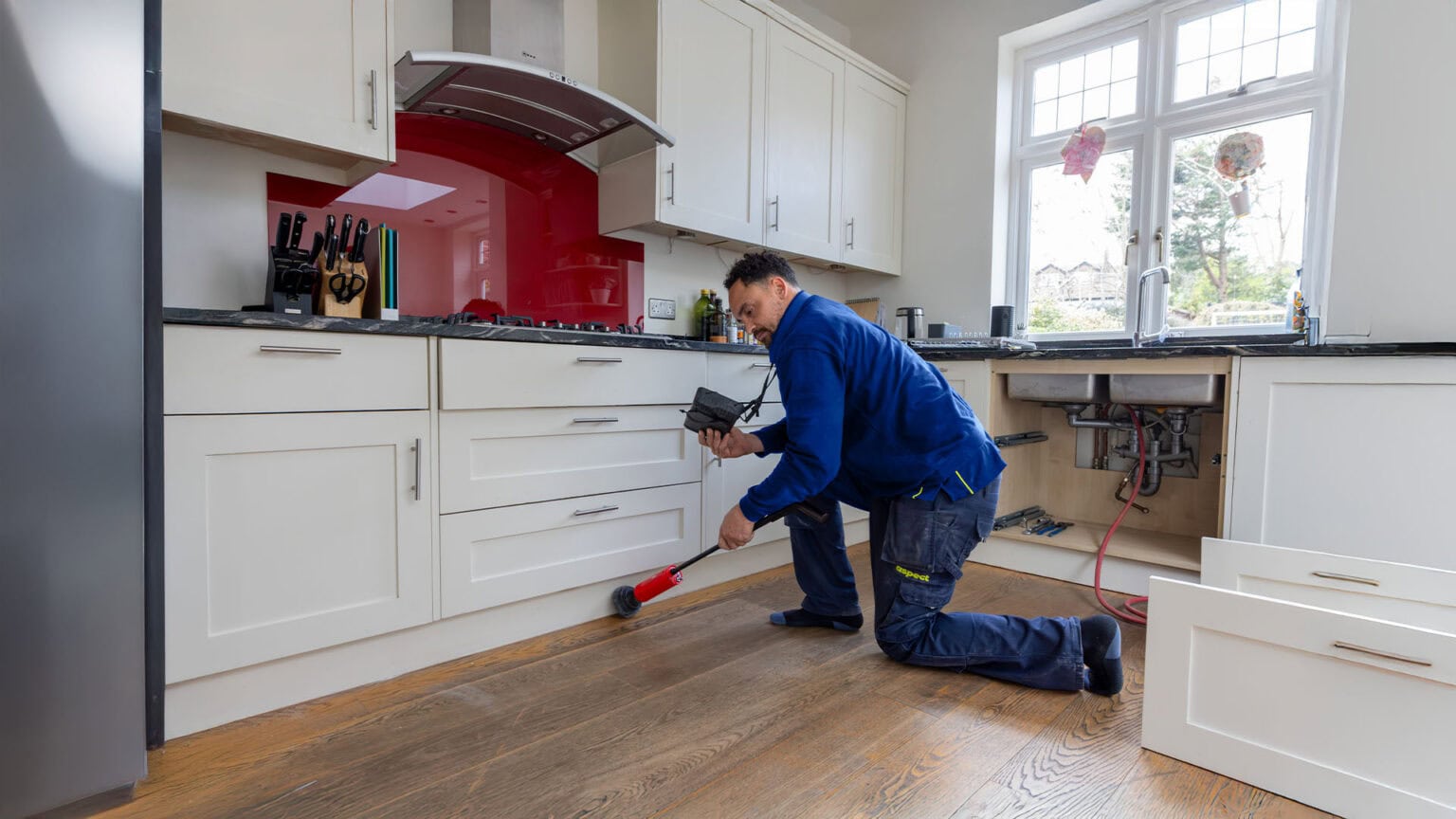 A gas engineer doing a tracer gas test to find a gas leak in a domestic kitchen.