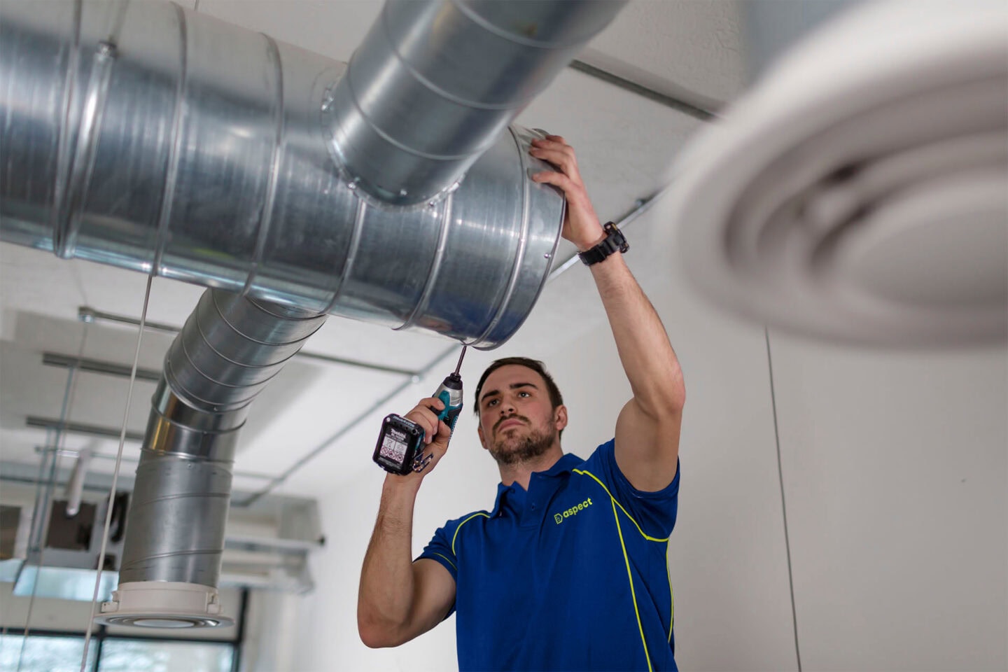 Aspect air con technician installing ventilation ducting.