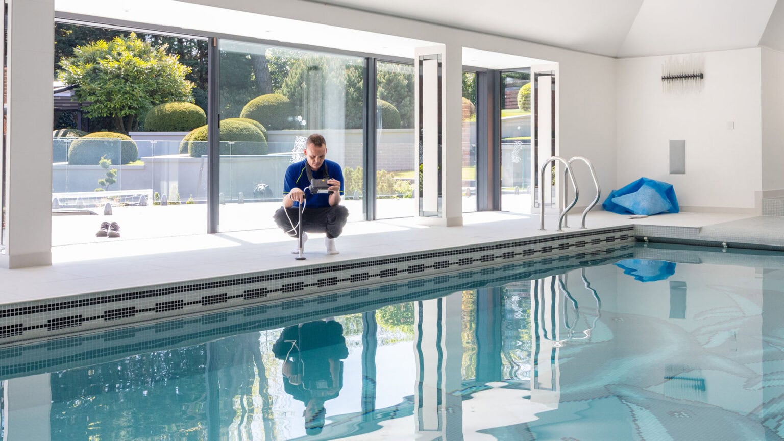 A leak detection specialist carrying out a tracer gas test next to an indoor swimming pool to find a concealed leak.