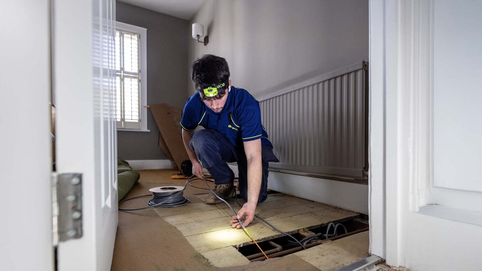 An Aspect electrician pulling electric cables from underneath floorboards to install a new circuit being installed.
